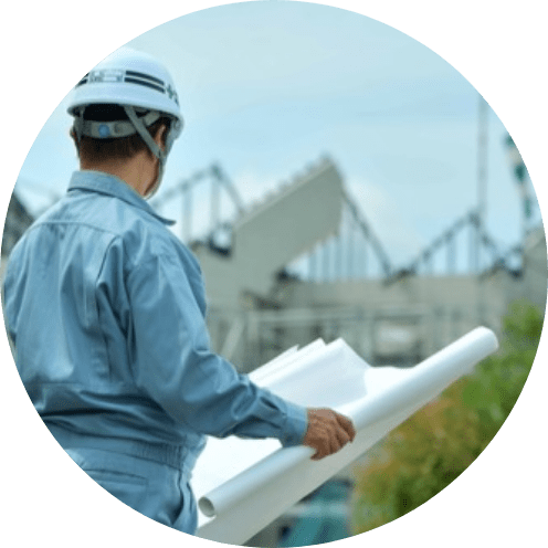 設計図を持ちヘルメッドを被った作業着の男性の後ろ姿の写真